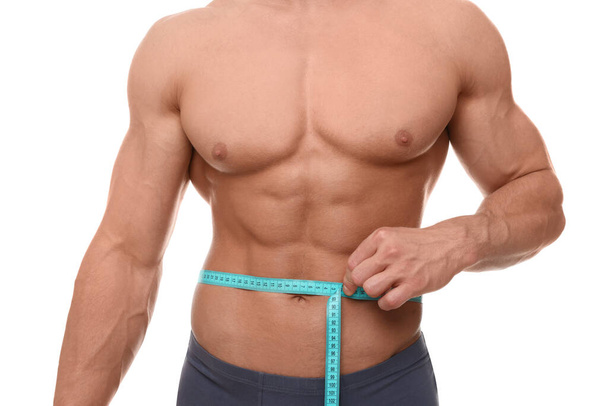 Athletic man measuring waist with tape on white background, closeup. Weight loss concept - Φωτογραφία, εικόνα