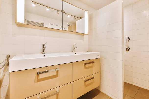ванная комната с двумя раковинами и зеркалом над раковиной - белая плитка на полу, а также бежевые шкафы - Фото, изображение