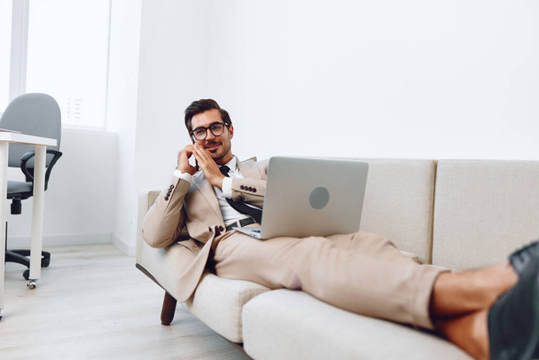 Mies hymyillä fiksu puhelu elämäntapa toimisto sohva työpuhelin istuu voittaja puhelu työpöytä video ammatti tietokone liikemies kannettava tietokone työpaikalla puhua - Valokuva, kuva