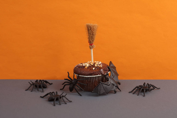 Feliz Dia das Bruxas. Bolo de chocolate ou cupcake com decoração halloween no fundo laranja. - Foto, Imagem