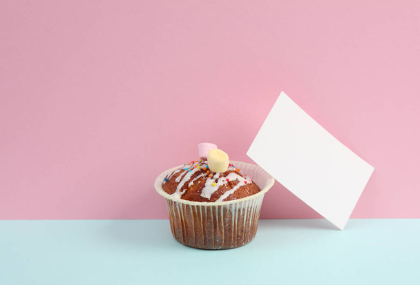 Muffin con una tarjeta de visita sobre un fondo azul-rosa. Identidad corporativa. Concepto alimenticio - Foto, imagen