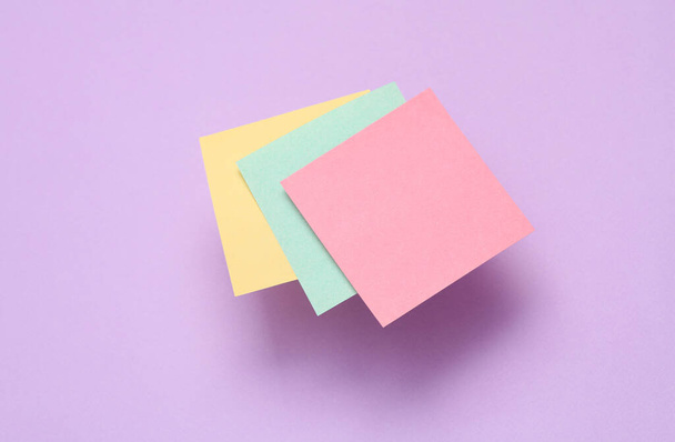 Memo vacío hojas cuadradas de papel sobre fondo púrpura - Foto, Imagen