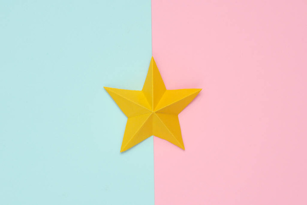 Una stella di carta origami su sfondo rosa pastello blu. Valutazione del servizio - Foto, immagini
