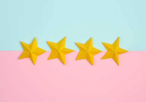 Quattro stelle di carta origami su sfondo rosa pastello blu. Valutazione del servizio - Foto, immagini