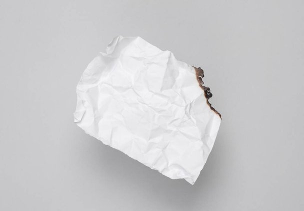 white crumpled sheet of paper charred on a gray background - Photo, Image