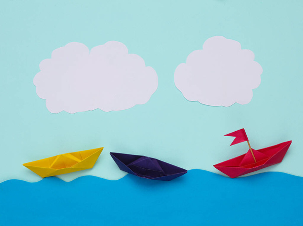 Scene of origami paper boats in the paper ocean against the sky with clouds. Children's creativity. Leadership concept - Photo, Image