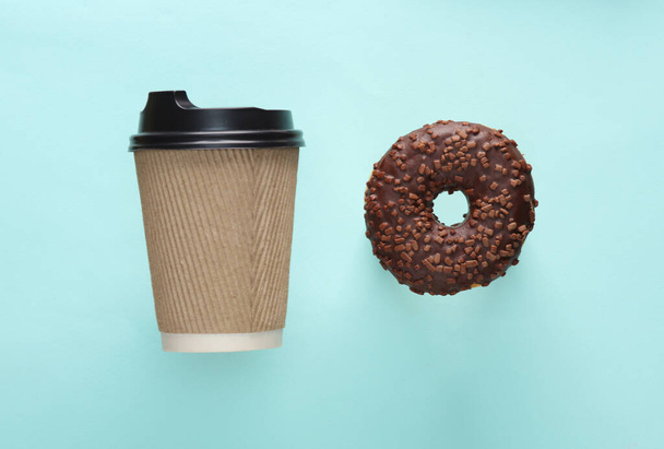 Pappbecher Kaffee zum Mitnehmen mit Schokoladen-Donut auf blauem Hintergrund - Foto, Bild