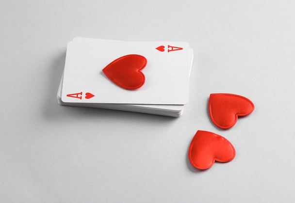 Ace of hearts with heart on top of stack of playing cards, gray background - Photo, Image