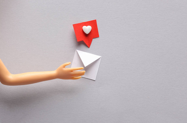 Mão de boneca segurando envelope de correio de notificação de corte de papel com mídia social como em fundo cinza. Layout minimalista criativo - Foto, Imagem