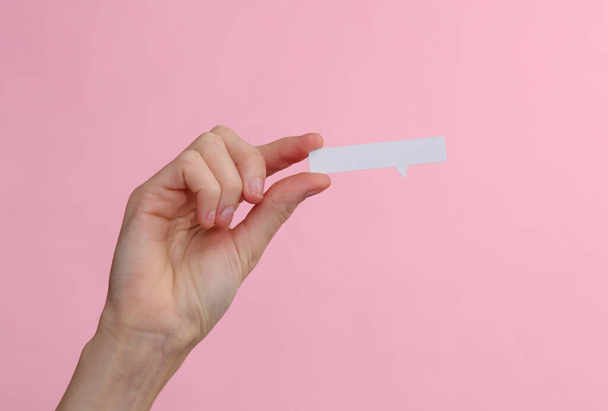 Female hand holding a speech bubble on a pink background - Zdjęcie, obraz