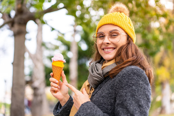 Brünette Frau mit einem Cornet-Eis im Freien und zeigt es - Foto, Bild