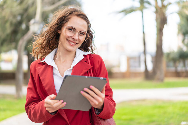 Young caucasian woman at outdoors holding a tablet - Фото, изображение