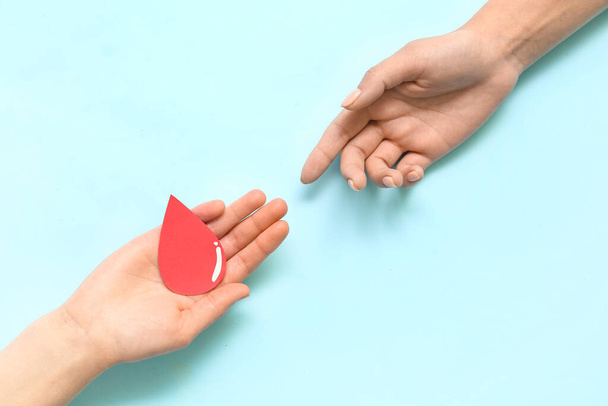 Women with paper blood drop on blue background. World Donor Day - Foto, Imagen