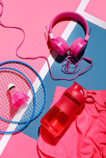 Bir şişe su, kulaklık, badminton raketleri ve renk arkaplanlı mekik sikli kompozisyon - Fotoğraf, Görsel