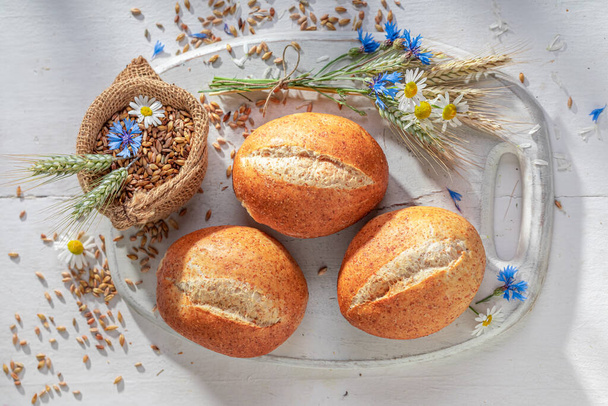 Homemade buns baked with organic wheat and flowers. Rolls surrounded by grain and field flowers. - Photo, image