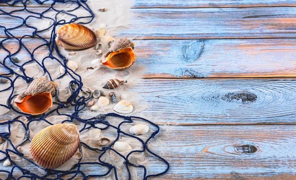 Grandes conchas marinas, red de pesca azul, arena sobre fondo de madera azul. Vacaciones de verano en el mar concepto - Foto, imagen