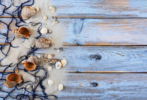 Sea background with big sea shells, fishing net and sand on wooden background, top view. Summer vacation concept - Foto, Imagem