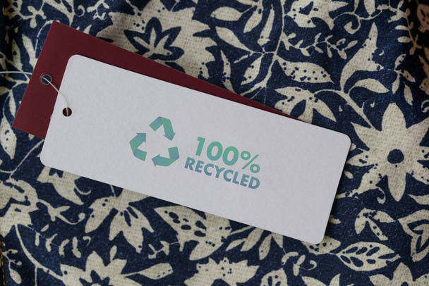 Lähikuva vaatteiden tag kierrätys kuvaketta. Kierrätystuotteiden käsite. Nollajäte, suistainale-tuotanto, ympäristön hoito ja uudelleenkäyttö - Valokuva, kuva