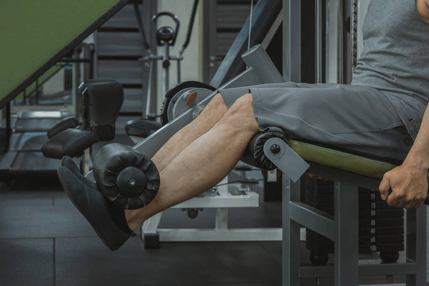 Προέκταση ποδιών άσκηση στον προσομοιωτή στο γυμναστήριο. Κοντινό πλάνο - Φωτογραφία, εικόνα