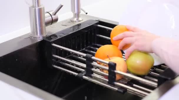 Mãos de uma mulher lavando uma maçã sobre a pia da cozinha, preparando um café da manhã fresco com frutas. Conceito de comida Vegan - Filmagem, Vídeo