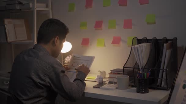 Työntekijöitä stressaa ja väsyttää. kiireinen paperitöiden kanssa Turhautuneita nuoria aasialaisia liikemiehiä, jotka työskentelevät työpöydällä täynnä papereita tietokoneella yrityksen toimistossa - Materiaali, video