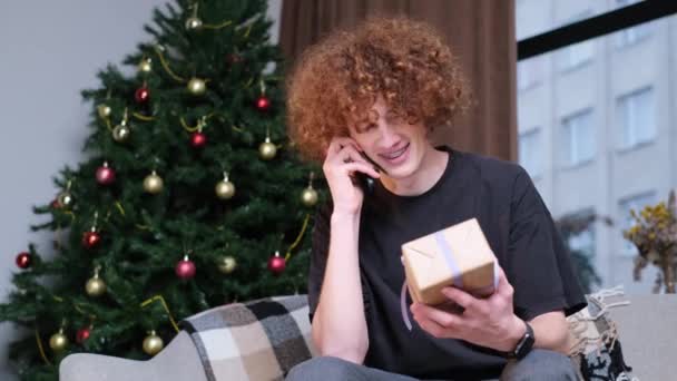 A fiatalember kapott egy újévi ajándékot. Karácsonyi ünnepség. Ajándékot adni. Boldog fiatalember.. - Felvétel, videó