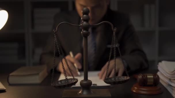Умный и профессиональный азиатский адвокат-мужчина в официальном костюме сидит за столом ночью в офисе. юрист, юридический консультант. - Кадры, видео