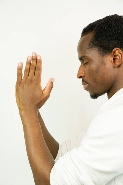 fiatal fekete férfi imádkozik, elszigetelt fehér háttér - Fotó, kép
