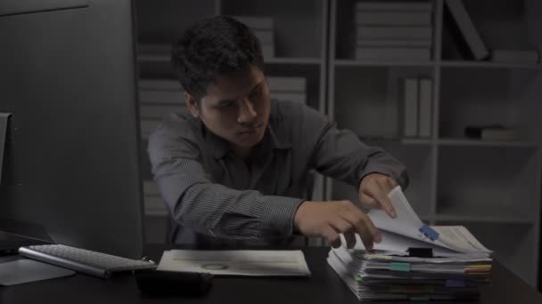 アジアの男性ビジネスマンは,財務文書やデスクトップコンピュータで働いて遅くまでオフィスで働いています, 残業サラリーマンコンセプト4k働く若い男 - 映像、動画