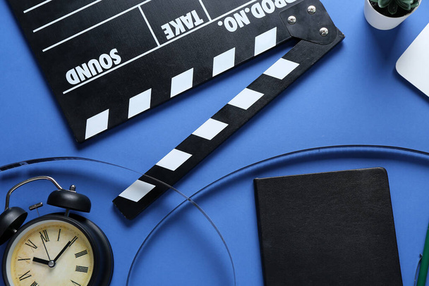 Quaderno con gobbo di film, bobina di film e sveglia su sfondo blu - Foto, immagini