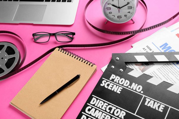 Notizbuch mit Filmklöppel, Filmrolle und Wecker auf rosa Hintergrund - Foto, Bild