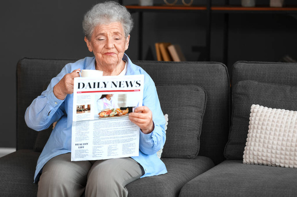 Mujer mayor con taza de café leyendo el periódico en casa - Foto, Imagen