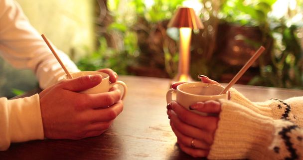 Крупный план рук влюбленной пары, сидящей за столом в кафе на романтическом свидании. Мужские и женские руки взаимодействуют друг с другом в момент романтической встречи влюбленной пары. - Фото, изображение