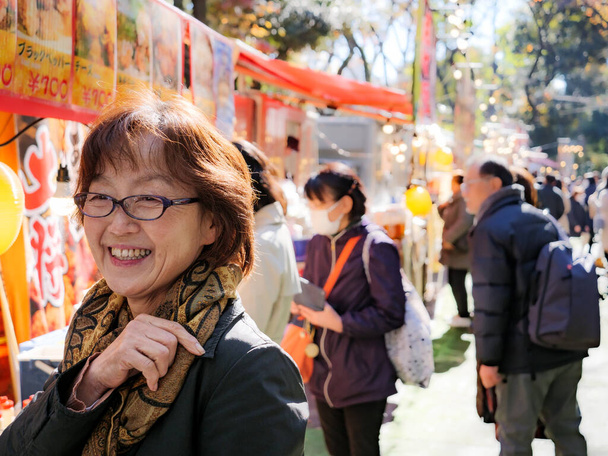 Een oudere Japanse vrouw glimlachend op een festival buiten - Foto, afbeelding