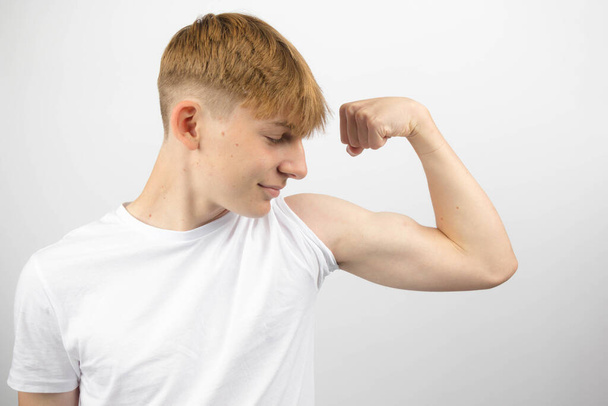 Retrato de un adolescente caucásico de 14 años flexionando su bíceps - Foto, imagen