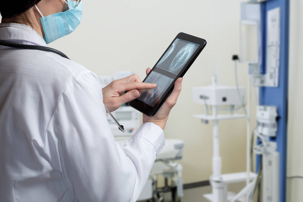 Le médecin regarde à travers les rayons X sur la tablette dans la salle des rayons X. - Photo, image