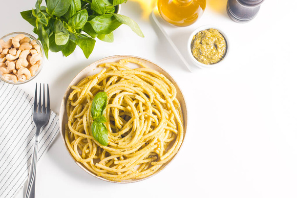 Makaron spaghetti z sosem pesto, bazylią, nerkowcem i parmezanem. Składniki.  - Zdjęcie, obraz