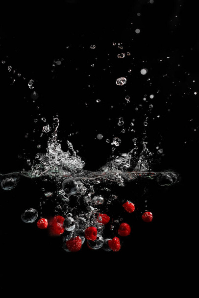 bright juicy fruits with splashes fly into the aquarium on a black background - Photo, Image