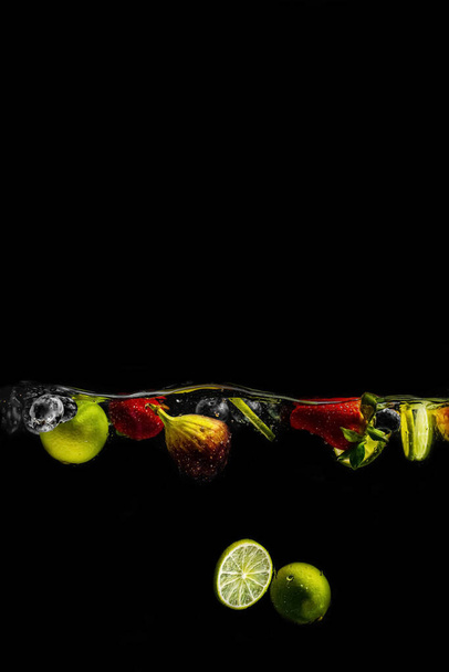 bright juicy fruits with splashes fly into the aquarium on a black background - Fotoğraf, Görsel