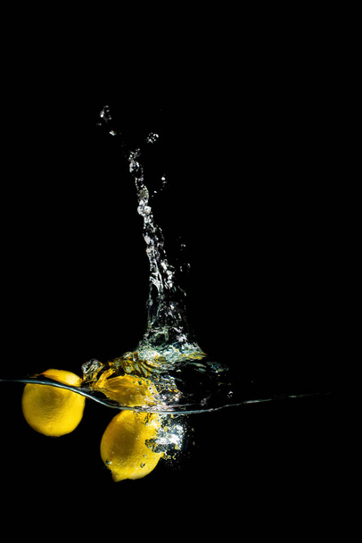 jasné šťavnaté ovoce s cákancemi létat do akvária na černém pozadí - Fotografie, Obrázek