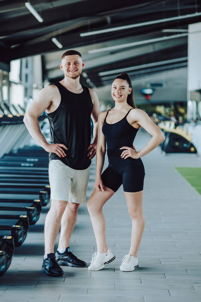Fitness enthusiasts Portrait of a man and woman in the gym, confident gazes at the camera. Fitness Partners Dynamic Gym Portrait of a Young Man and Woman - Fotó, kép