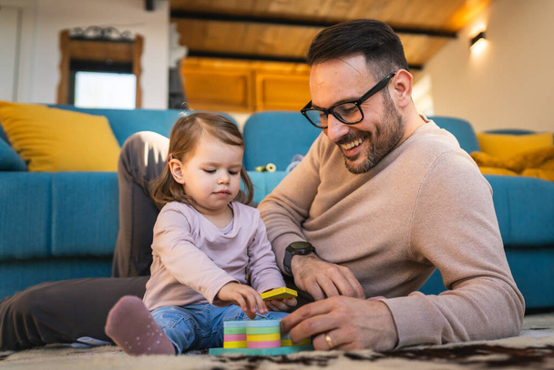 Apa és lánya játszani a padlón otthon érett felnőtt kaukázusi férfi játszani az ő két éves gyermek kisbaba lány szórakozás nevelés és kötődés családi idő koncepció másolja tér valós emberek - Fotó, kép
