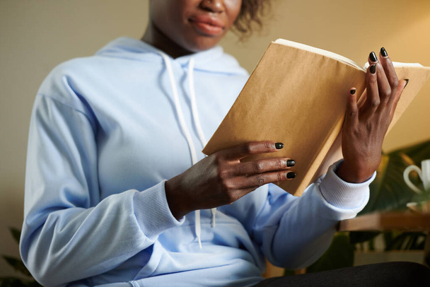 Imagen recortada de estudiante universitario en azul claro con capucha libro de lectura para la clase - Foto, Imagen