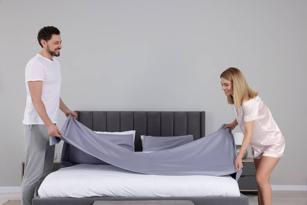 Couple changing bed linens in room. Domestic chores - Foto, Bild
