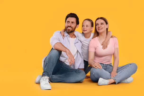 Happy family on orange background, space for text - Foto, afbeelding
