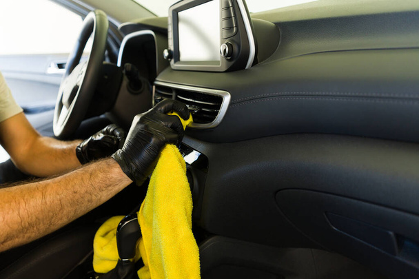 Primer plano de un trabajador masculino manos limpieza de los respiraderos del coche del cliente con tela en el lavado del coche - Foto, imagen