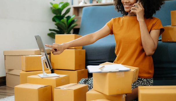 Young woman holding a smartphone, tablet showing payment success and credit card with yellow parcel box as online shopping concept  in home offic - Fotoğraf, Görsel