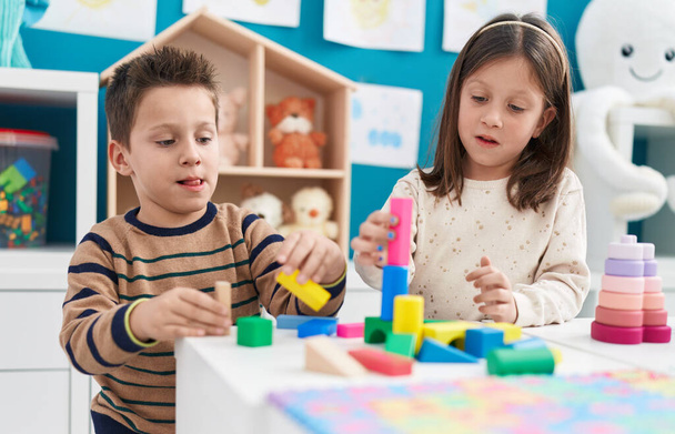Adorable garçon et fille jouant avec des blocs de construction assis sur la table à la maternelle - Photo, image