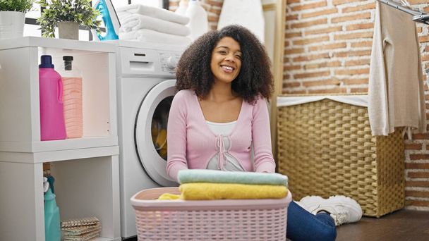 African american woman smiling confident washing clothes at laundry room - Fotó, kép