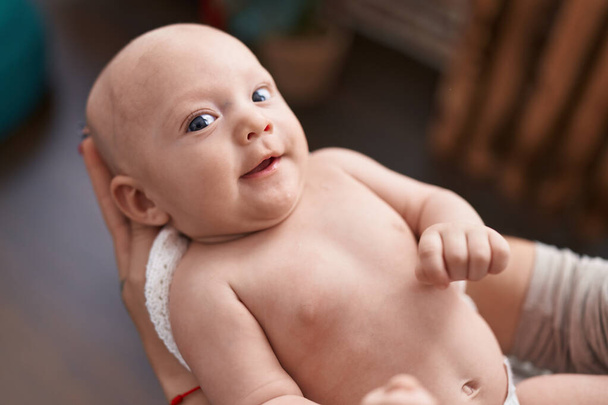Adorável bebê caucasiano sorrindo confiante deitado em mãos em casa - Foto, Imagem
